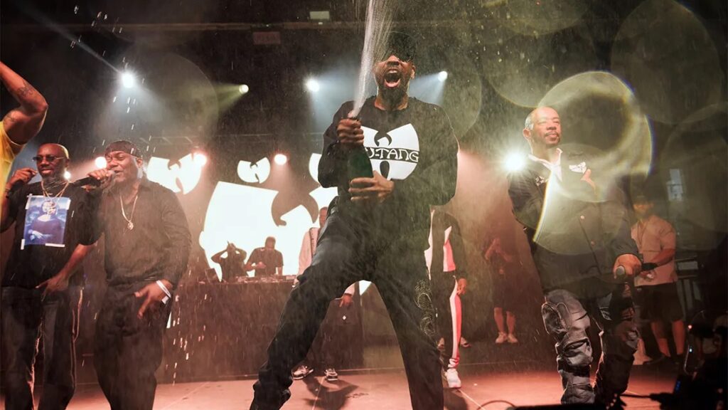 A group of artists pours champagne on stage